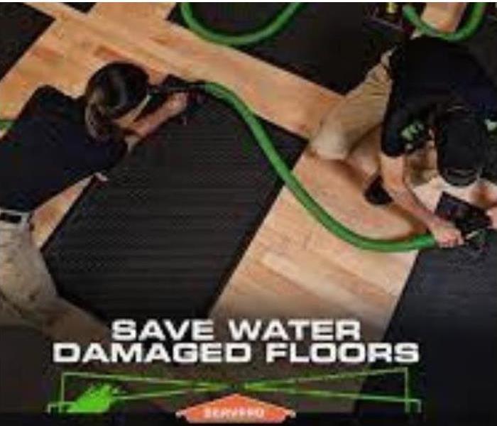 SERVPRO technicians installing a floor mat drying system to save water damaged floors
